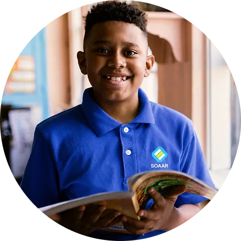 SOAAR student smiling while holding a book